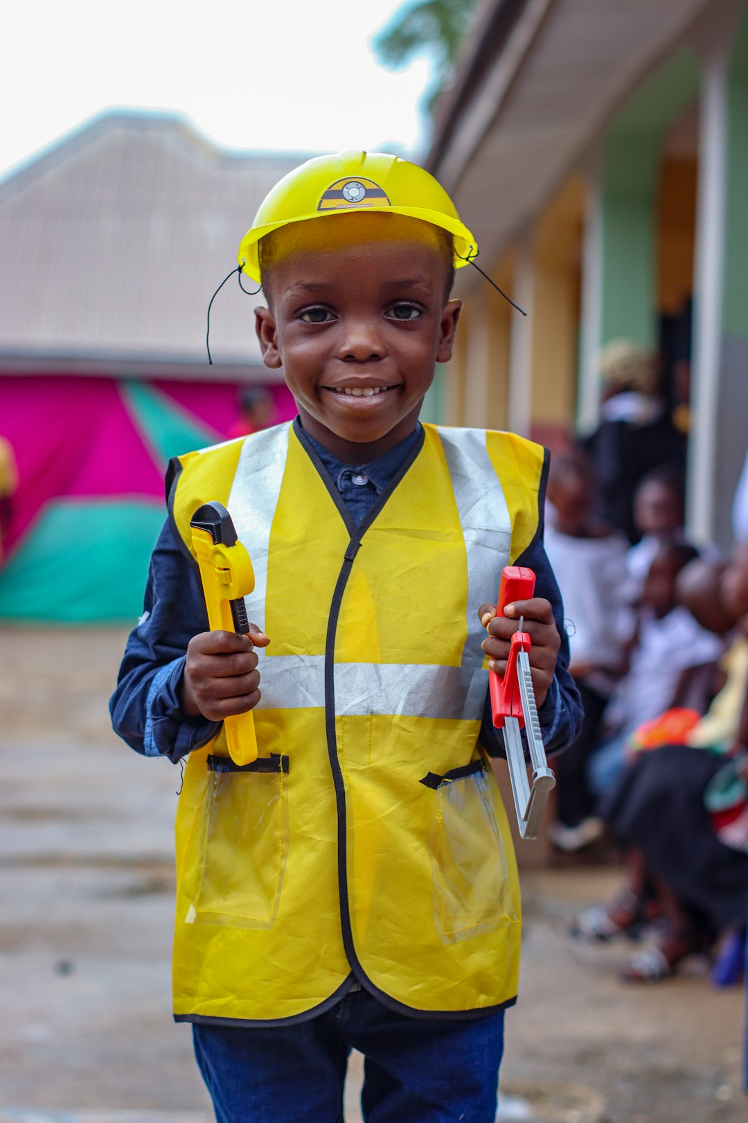 Photo by Prince Kwembe A young boy wearing a safety vest and holding a tool